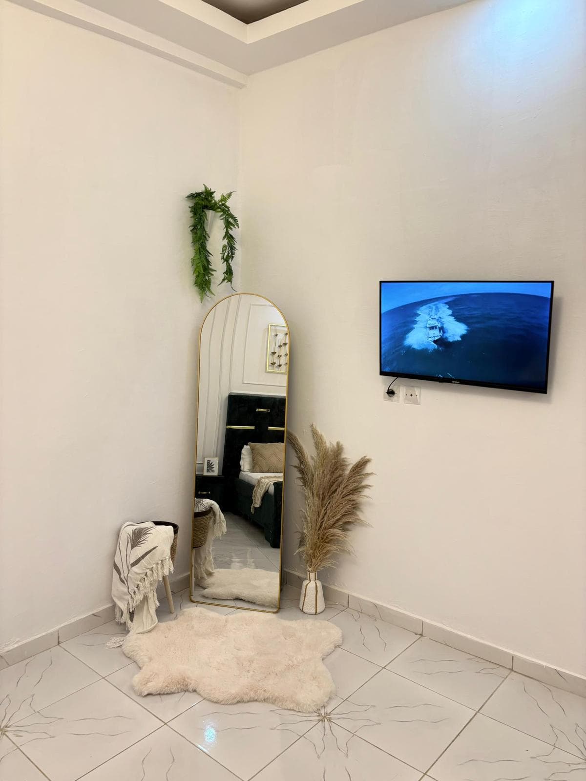 Coin chambre avec TV murale et miroir pleine hauteur