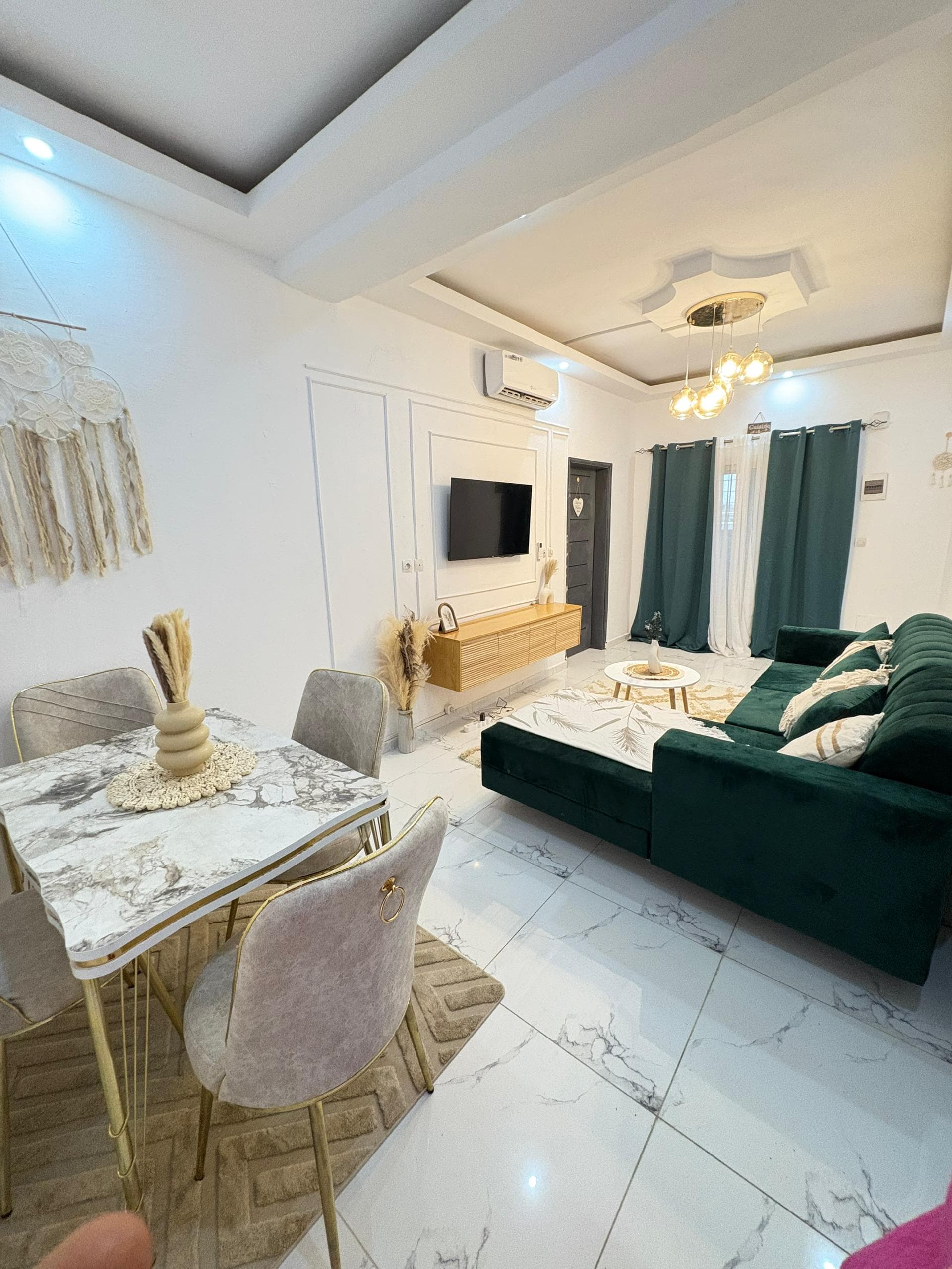 Salon principal avec coin repas, TV et canapé vert